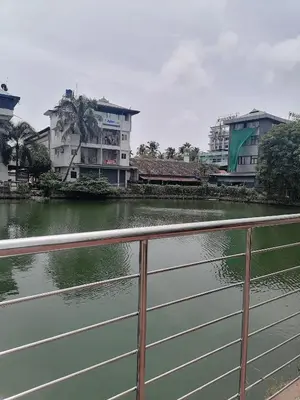 a fence next to a body of water with buildings at Green Garden Apartments in Kodungallūr