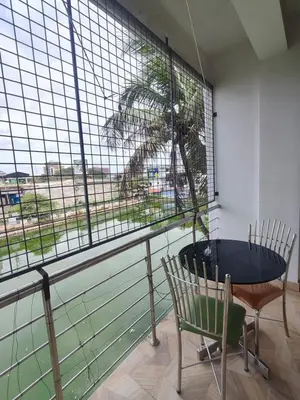 a table and a chair in a room with a window at Green Garden Apartments in Kodungallūr