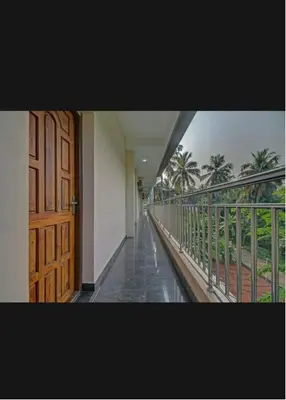 a hallway with a door and a balcony with palm trees at Subramania Arcade in Trichūr