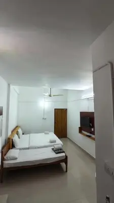 a large white room with a bed and a tv at NIRVANA HOLISTIC LIVING in Varagampadi