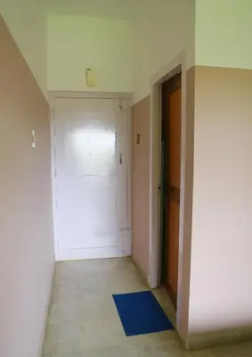 an empty room with a white door and a blue rug at Chakalakkal Residency in Sultan Bathery