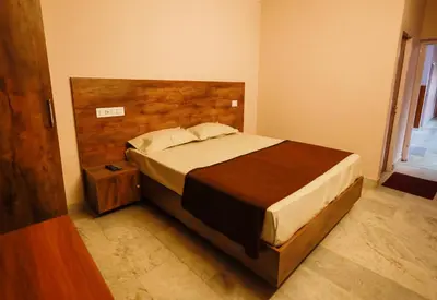 a bedroom with a large bed with a wooden headboard at Chakalakkal Residency in Sultan Bathery