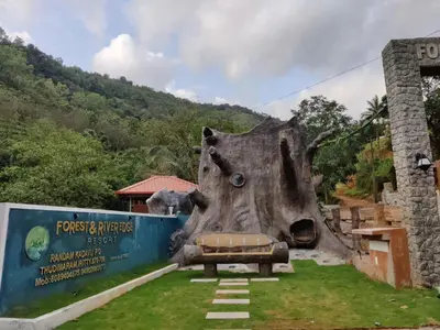 a statue of a tree stump with a bed in the grass at Forest and River Edge Resort in Kannur