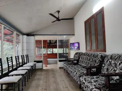a living room with a couch and chairs and a ceiling fan at Forest and River Edge Resort in Kannur