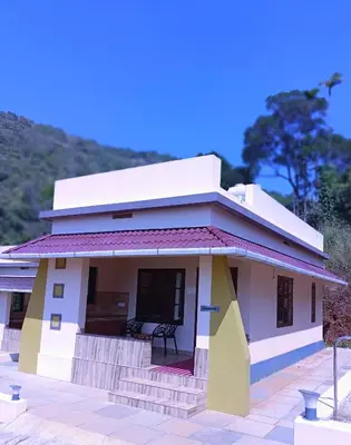 a small white house with a bench in front of it at Forest and River Edge Resort in Kannur