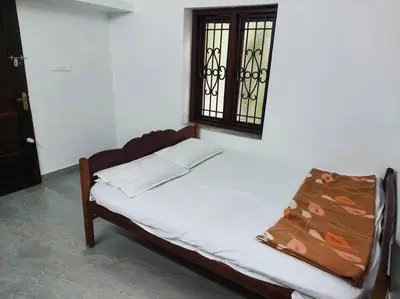 a small bed in a room with a window at Forestay -3 BHK Villa Kochi in Pallipuram