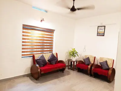 a living room with two chairs and a window at Forestay -3 BHK Villa Kochi in Pallipuram