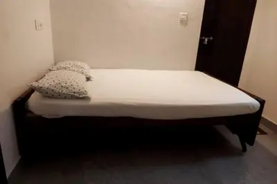 a small bed in a small room with white sheets and pillows at Forestay -3 BHK Villa Kochi in Pallipuram