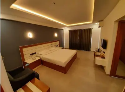a bedroom with a bed and a couch and a chair at Ashirvad Lawns Hotel & Convention Centre in Kozhikode