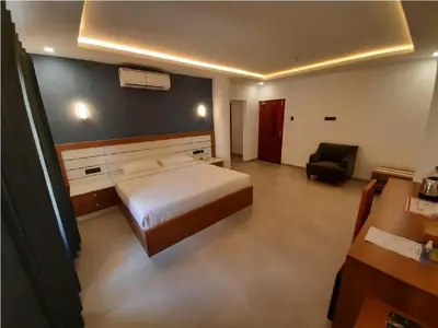 a bedroom with a bed and a chair in it at Ashirvad Lawns Hotel & Convention Centre in Kozhikode