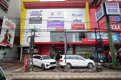 two white cars parked in front of a building at Emarald Hotel Calicut in Kozhikode