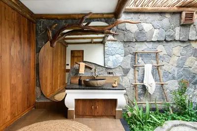 a bathroom with a sink and a stone wall at Earthitects Holiday Experiences,Wayanad in Kalpetta