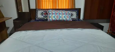 a bed in a bedroom with an orange curtain at NEST Mdy in Mananthavady