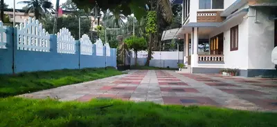 a house with a white picket fence and a sidewalk at NEST Mdy in Mananthavady