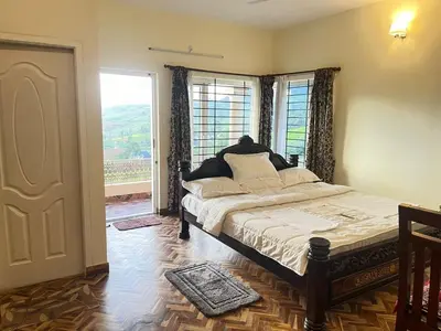 a bedroom with a bed and a large window at Mysterious mountain in Ooty