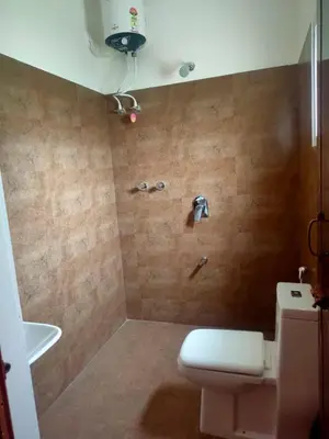 a bathroom with a white toilet and a shower at Empra Exotica in Madikeri