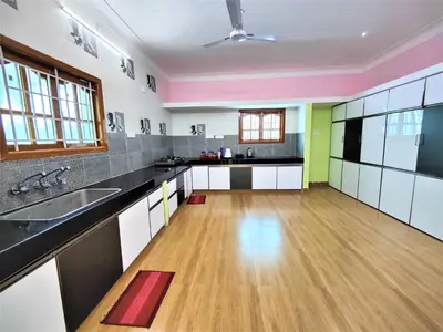 a large kitchen with black and white cabinets and a wooden floor at Coimbatore Premium Private Villa a FAMILY RESORT kids, celebration hall in Coimbatore