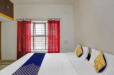 a bedroom with a large bed with red curtains at Hotel O Vishu Moni Residency in Mysore