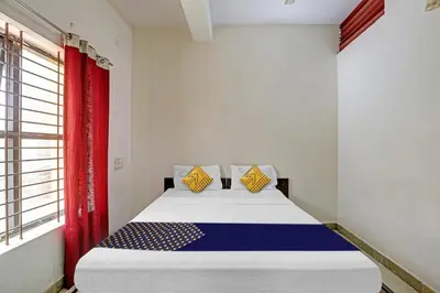 a bedroom with a bed with a red curtain at Hotel O Vishu Moni Residency in Mysore