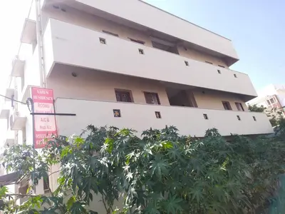 a building with a tree in front of it at Varun residency in Coimbatore