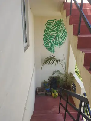 a staircase with a green leaf mural on the wall at SHI's Bhairavi Peaceful 2bhk villa - - On the way 2 isha-Adiyogi , Maruthamalai in Coimbatore