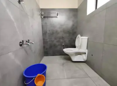 a bathroom with a toilet and a blue trash can at Hotel Mothimahal in Trichūr