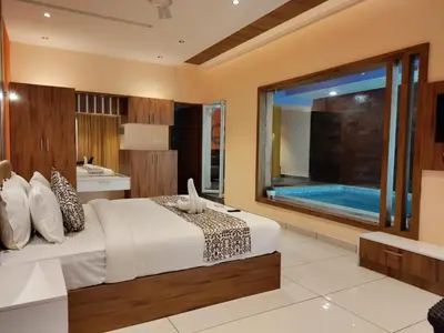 a bedroom with a bed and a swimming pool at Karapuzha Village Resort in Wayanad