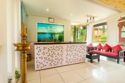 a living room with a tv and a red couch at Karapuzha Village Resort in Wayanad