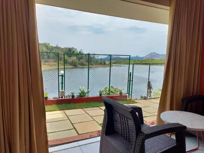 a view of a lake from a balcony with two chairs at Karapuzha Village Resort in Wayanad