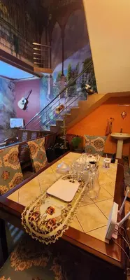 a table with wine glasses and a table with stairs at JJ's White House in Trichūr