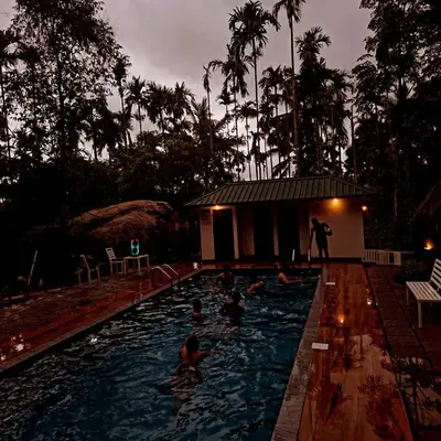 a group of people in a swimming pool at night at Cave Valley Wayanad in Ambalavayal