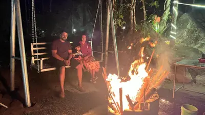 a family sitting on a swing next to a fire at Cave Valley Wayanad in Ambalavayal