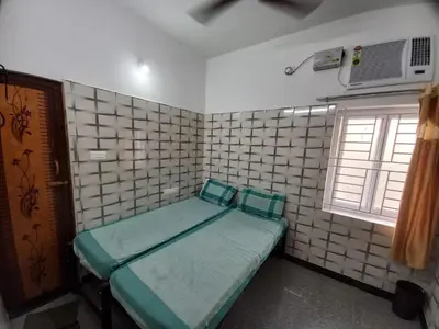 a small room with a green bed in it at Lakshmi Paradise Lodge A/C in Pollāchi