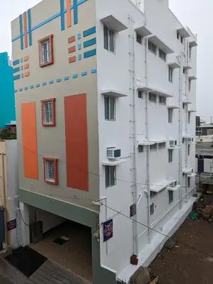 a white building with colorful doors and windows at Lakshmi Paradise Lodge A/C in Pollāchi