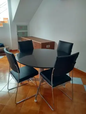 a table and four chairs in a room at The Orange Home in Kotagiri