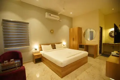 a bedroom with a white bed and a chair at Hotel PSY in Mettuppālaiyam