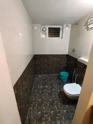 a bathroom with a toilet and a tile floor at Hotel PSY in Mettuppālaiyam