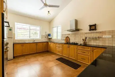 a large kitchen with wooden cabinets and a ceiling fan at ama Stays & Trails Arcadia, Coorg in Madikeri