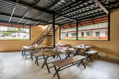 a restaurant with wooden tables and benches and windows at Hatti Eden Coorg in Gonikoppal