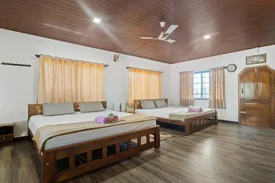 two beds in a room with wooden ceilings and wood floors at Hatti Eden Coorg in Gonikoppal