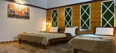 two beds in a room with stained glass windows at Hatti Eden Coorg in Gonikoppal