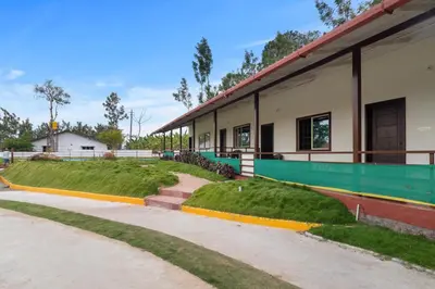 a building with a sidewalk next to a building with grass at Hatti Eden Coorg in Gonikoppal