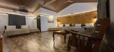 a hotel room with two beds and a table at Hatti Eden Coorg in Gonikoppal
