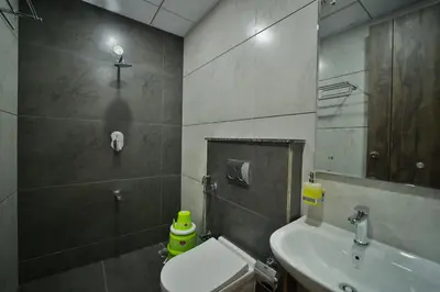 a bathroom with a sink and a toilet and a mirror at The Mysore Grand in Mysore