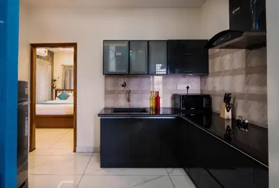 a kitchen with black cabinets and a room with a bed at Royal Tusker Luxury Service Apartments in Mysore