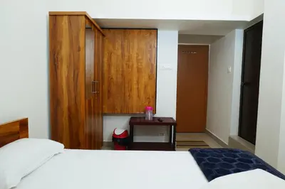 a bedroom with a white bed and a wooden cabinet at Hillside Hideaway Gudalur in Gūdalūr