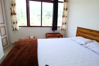 a bedroom with a large white bed and a window at Hillside Hideaway Gudalur in Gūdalūr