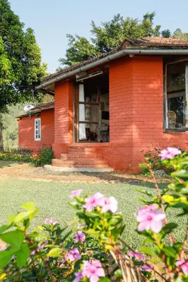 a red brick house with a broken window at DEVASHOLA HOMESTAY in Coonoor