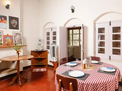 a dining room with a table with a red and white table cloth at DEVASHOLA HOMESTAY in Coonoor