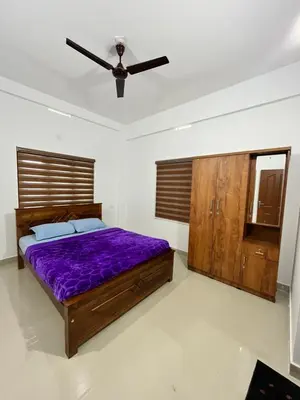 a bedroom with a purple bed and a ceiling fan at Wayanad Biriyomz Residency, Kalpatta, Low Cost Rooms and Deluxe Apartment in Kalpetta